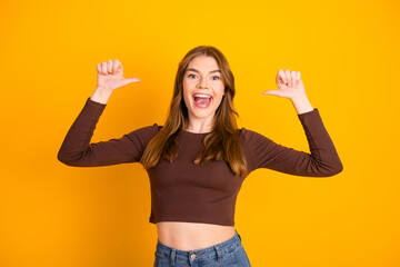 Young woman in casual brown crop top on vibrant yellow background radiates happiness and...