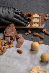 The pastry chef in black gloves shapes the candy dough