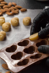 The pastry chef in black gloves shapes the candy dough