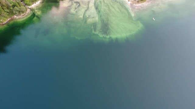 Aerial view of Lago del Predil. Turquoise Italian lake with clear water, supboards, spruce forest and dry river
