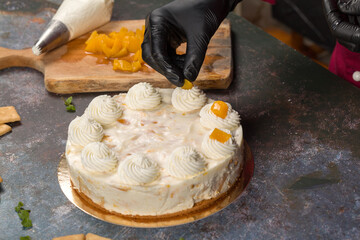 Confectioner decorates freshly baked cake with slices of peach