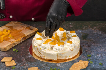 Confectioner decorates freshly baked cake with slices of peach