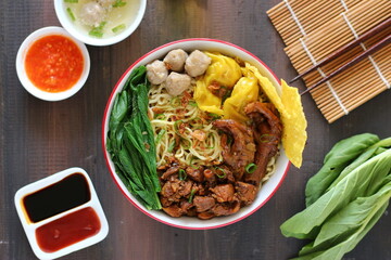 Mie ayam baso. noodle with chopped chicken and meat balls. served with cracker and boiled vegetables.