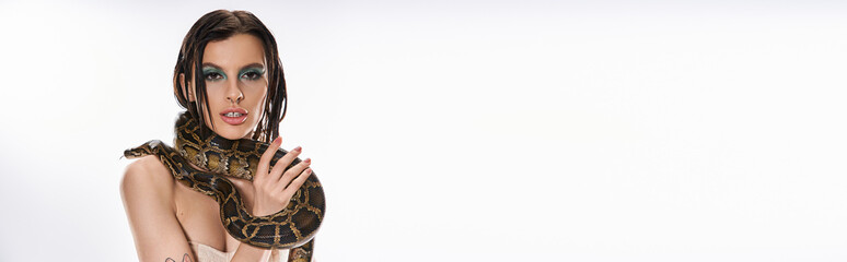 Young beautiful woman embraces a snake in an artistic and bold presentation of nature and elegance