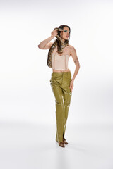 Young beautiful woman poses confidently with an elegant snake in a minimalist setting