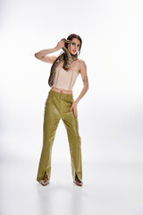 Young beautiful woman gracefully poses with a snake in a stylish outfit under bright lights