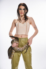 Young beautiful woman holds a snake with confidence in a striking pose