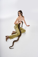 Young beautiful woman exudes confidence while posing with a snake in an artistic studio setting