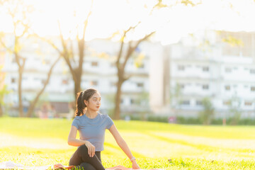 Asian woman stretches her body and neck after jogging at a city park, enjoying outdoor sports...