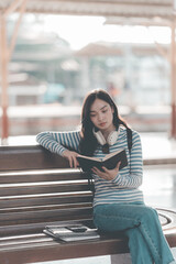 Young woman traveler wearing backpack waiting for train at train station Summer vacation and...