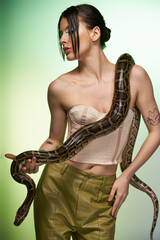 Stunning portrait of a young woman confidently posing with a large snake and a vivid backdrop