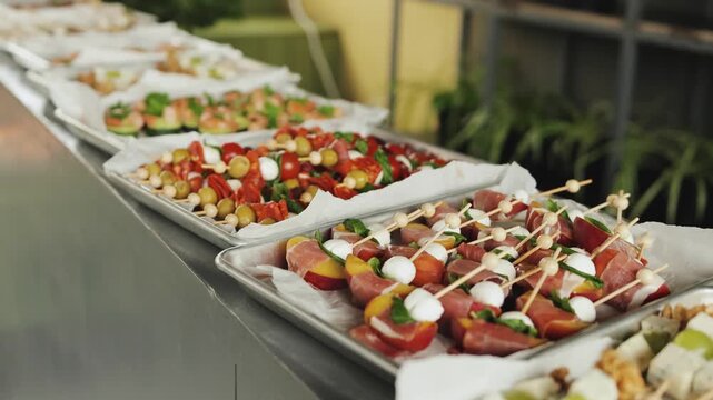 Buffet table for catering in a street cafe. Trays with appetizers of meat, fruit, olives, grapes and cheese.