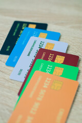 Colorful array of credit cards arranged on a light wooden surface in a vertical shot