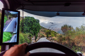 Driver’s view from a truck on a narrow mountain road under cloudy skies