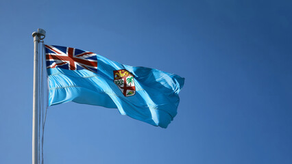 Fiji flag waving gracefully under a clear blue sky at a high pole