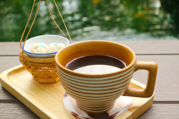Cup of Black Coffee Served with aromatic Thai tiny biscuits called Kleeb Lamduan, meaning Lamduan...