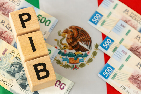 Mexico economy. The word PIB (Gross Domestic Product) written on wooden dice, with Mexican money in yellow, Mexican flag.