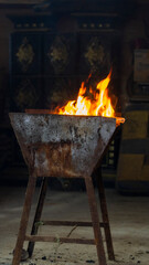 A vertical shot of a fire burning in a rusty, metal container, a rustic scene