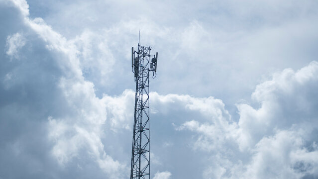 A cell phone tower stands tall against a dramatic, cloudy sky, symbolizing modern communication
