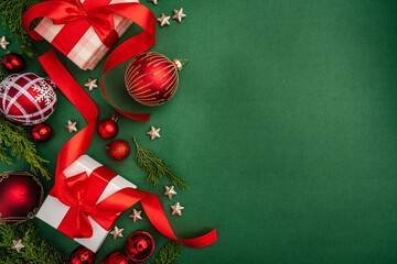 Holiday flat lay with red and white wrapped gifts, baubles, ribbon, stars, and greenery on a green...