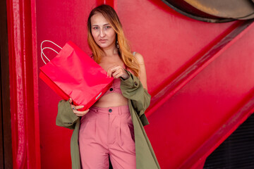 Fashion model holding shopping bag against red background