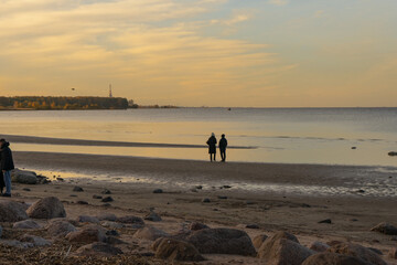 Two people with reflective mood walking by the sea against twilight bay background