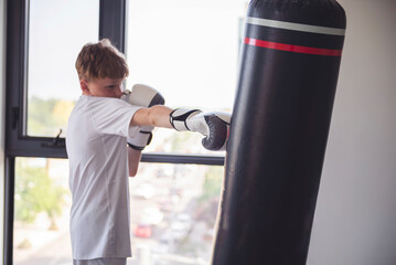 teenager in boxing gloves trains with punching bag
