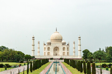 Obraz premium Taj Mahal reflecting in the water channel with tourists walking in Agra, India