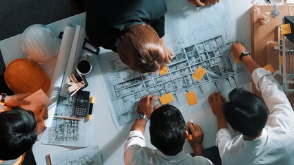 Top down view of skilled engineer team talking about house construction. Aerial view of group of architect or designer discussing and writing sticky note to brainstorm about blueprint. Alimentation.