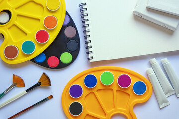 Sketchbook, palettes, watercolor paints, canvas and paintbrushes. Back to school concept. Copy space