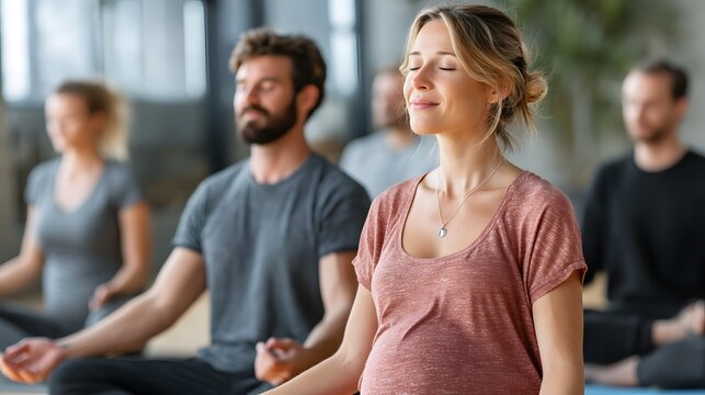 Pregnant woman and partner attending prenatal class practicing breathing exercises with calm instructor