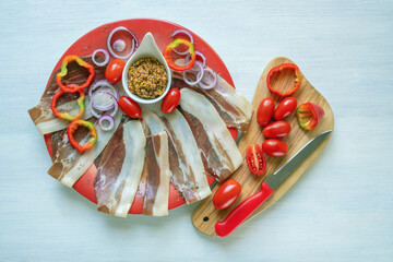 Balkan cuisine. Slices of prsut: dry-cured ham,  and mustard on red plate.  White rustic table,...