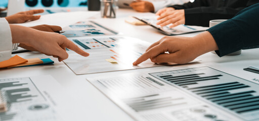 A collaborative business meeting scene showcasing diverse professionals engaging in analysis of charts and graphs, highlighting teamwork and communication in a modern office setting. SACTR