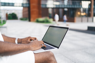 Close-up of hands typing on laptop outdoors, emphasizing detail of remote tech use and seamless digital interface in contemporary workflow.