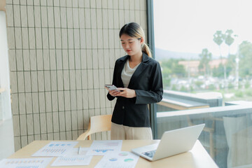Asian female accountant stressed while finalizing financial reports, holding head in frustration.
