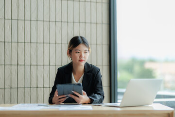 Asian female accountant reviewing annual business revenue reports with focus and professionalism.