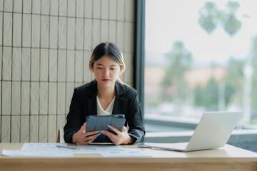 Asian female accountant reviewing annual business revenue reports with focus and professionalism.