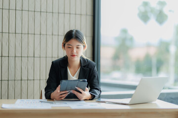 Asian female accountant reviewing annual business revenue reports with focus and professionalism.