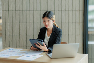Professional Asian accountant calculating and summarizing annual income for a company.