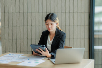 Professional Asian accountant calculating and summarizing annual income for a company.