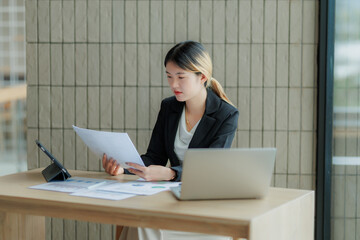 Professional Asian accountant calculating and summarizing annual income for a company.