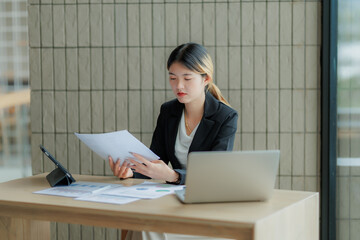 Professional Asian accountant calculating and summarizing annual income for a company.
