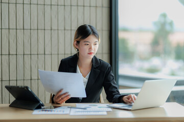 Professional Asian accountant calculating and summarizing annual income for a company.