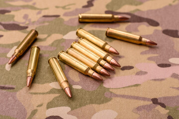 Machine gun cartridges on a camouflage background, military wallpaper. Camouflage background