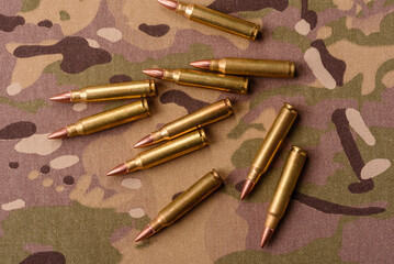 Machine gun cartridges on a camouflage background, military wallpaper. Camouflage background