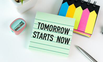 A green sticky note with the words Tomorrow Starts Now written on it