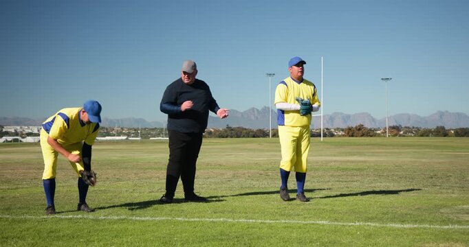 Clapping baseball coach guiding players practicing throws on field, with gloves and form drills