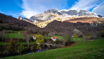Autumnal mountain valley with stone bridge and village houses.
