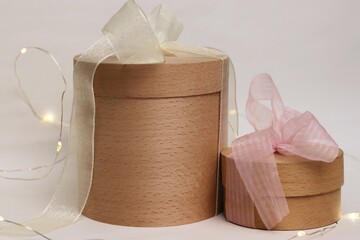 Cylindrical wooden gift boxes with ribbons and garlands are a stylish solution for festive design,...