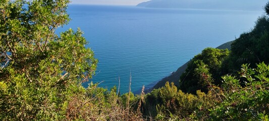 Crystal clear sea with mountain backdrop and green landscape